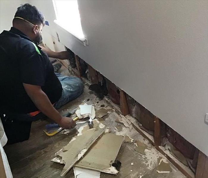 male SERVPRO employee on floor removing drywall