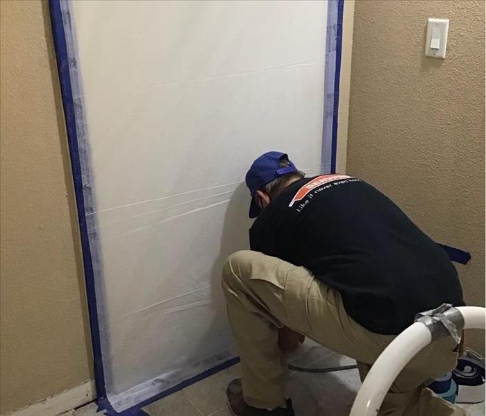 male SERVPRO employee securing containment sheet in doorway