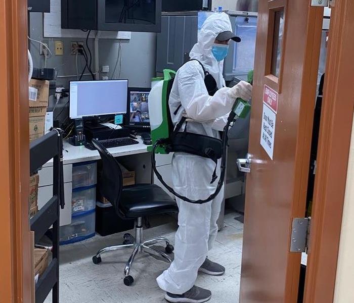 male SERVPRO employee in full PPE cleaning with hospital grade solution