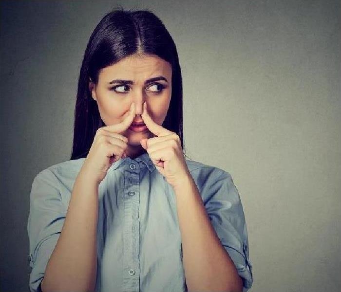 brunette woman plugging her nose with her hands