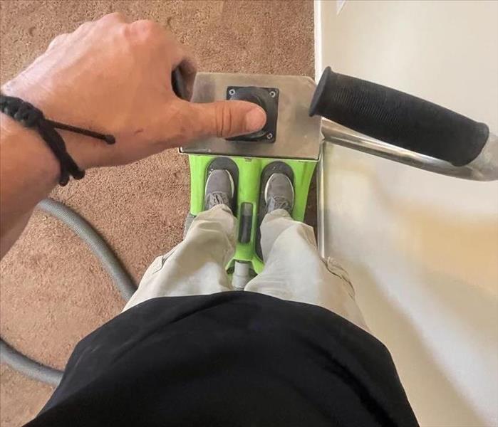 Male SERVPRO employee using extractor to clean up water damage in a home